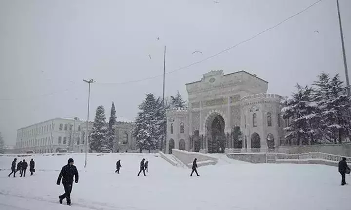 Kar yağışı altında beyaza bürünen İstanbul Üniversitesi’nin tarihi kapısı ve kampüs çevresi.