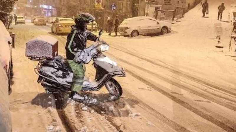 : Kışlık kıyafetler giymiş bir kurye ya da teslimat görevlisinin fotoğrafı. 