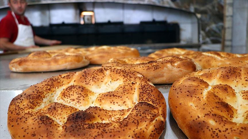 . Fırın çalışanı, kırmızı önlük ve beyaz önlük giyerek taş fırında pide pişiriyor. 2025 Ramazan pidesi fiyatları