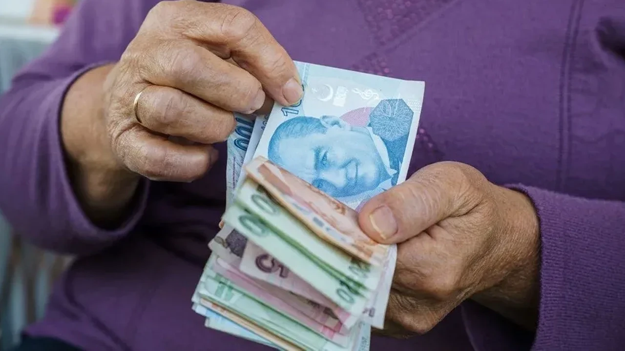 Bir kişinin cüzdanından Türk lirası banknotları (100 TL ve 200 TL) çıkardığı yakın çekim fotoğrafı. Emekli banka promosyonu haberleri için uygun, finansal güvenliği ve nakit parayı temsil eden görsel.