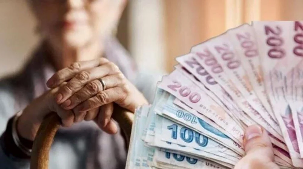 Bir emeklinin baston tutarken diğer elinde yelpaze şeklinde düzenlenmiş 100 TL ve 200 TL banknotları aldığı anı gösteren fotoğraf. Emekli banka promosyonu haberleri için ideal, finansal destek ve yaşlılık temalı görsel.