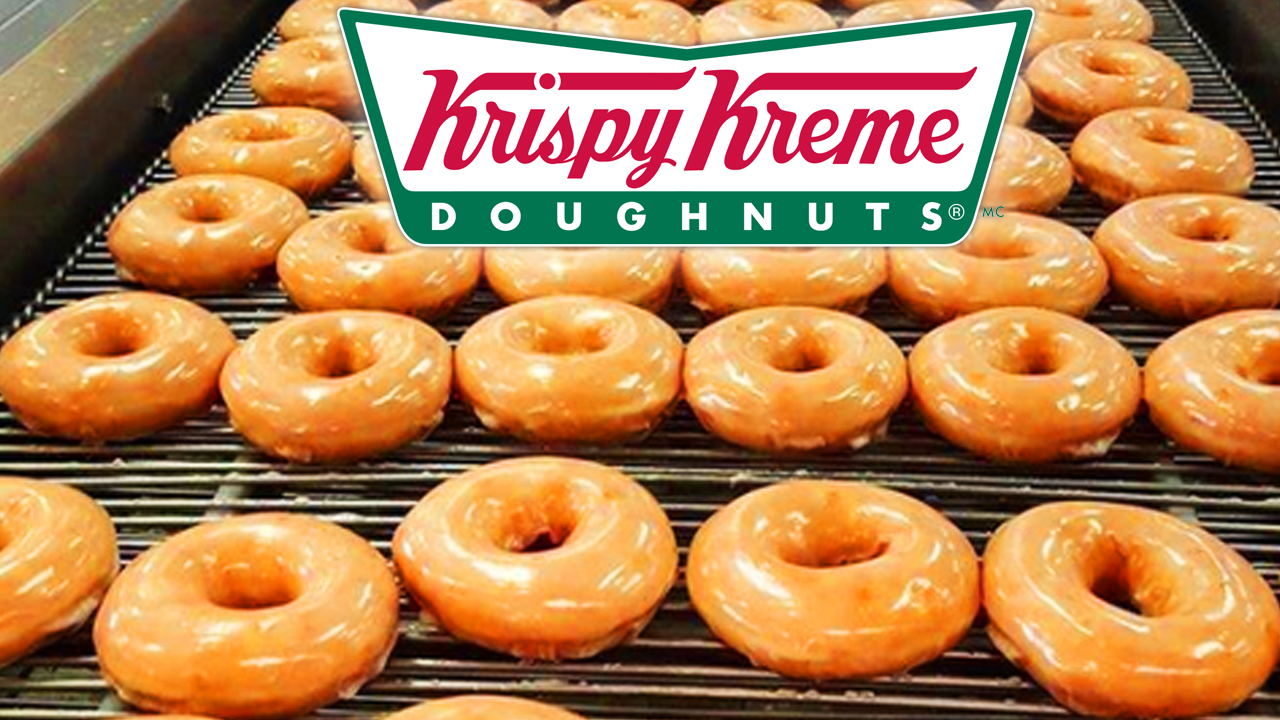 Krispy Kreme Türkiye’nin donut üretim hattı, taze ve parlak glazeli donutların konveyör bandından geçtiği bir görüntü, 2025 finansal kriz haberleri arka planında.
