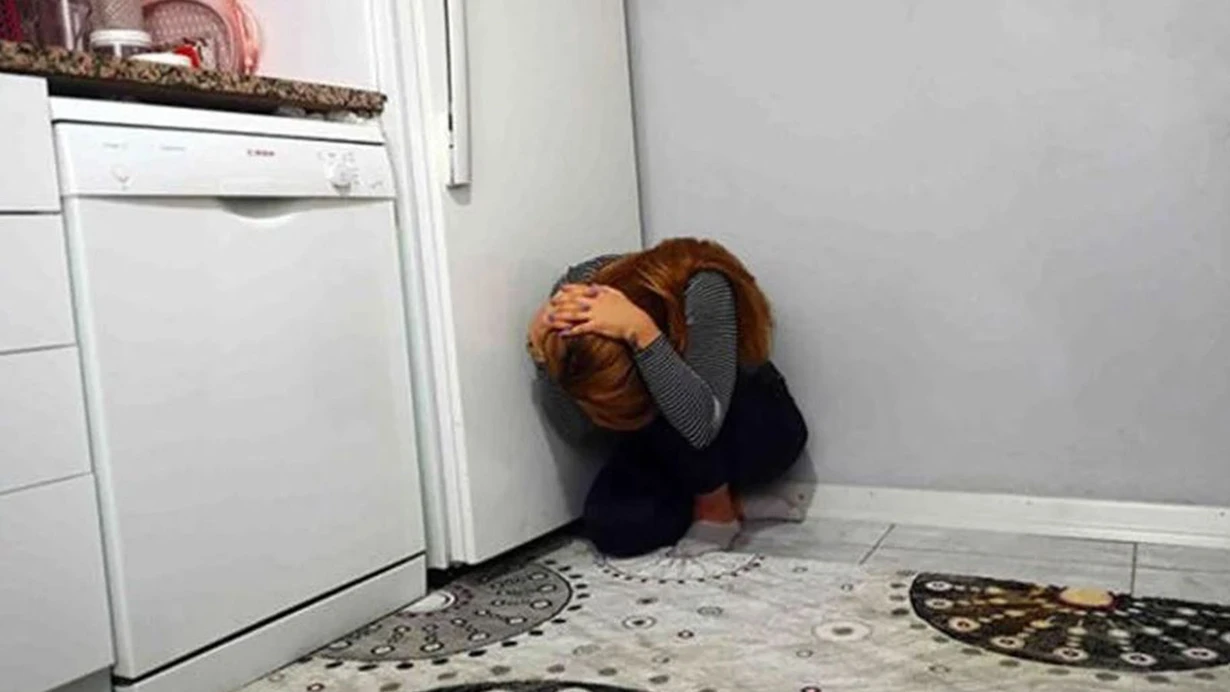Deprem anında hayat üçgeni pozisyonu alan bir kadın. Koruyucu eşya yanına çömelmiş, başını elleriyle koruyor. Güvenli yaşam alanı oluşturma örneği.